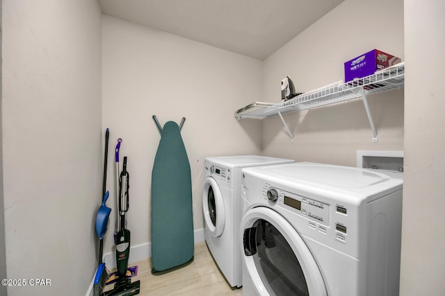 laundry area featuring baseboards, independent washer and dryer, light wood-style flooring, and laundry area