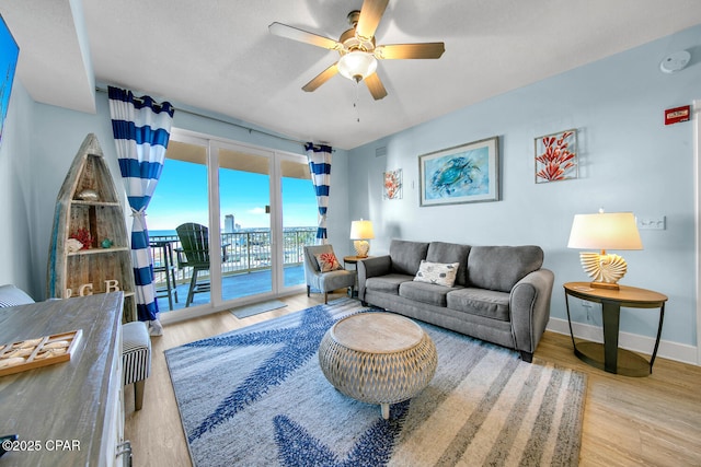 living area with a ceiling fan, wood finished floors, and baseboards