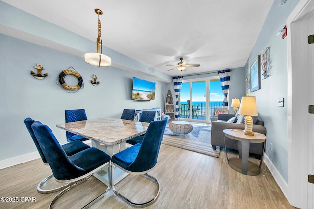 dining space with a ceiling fan, wood finished floors, and baseboards