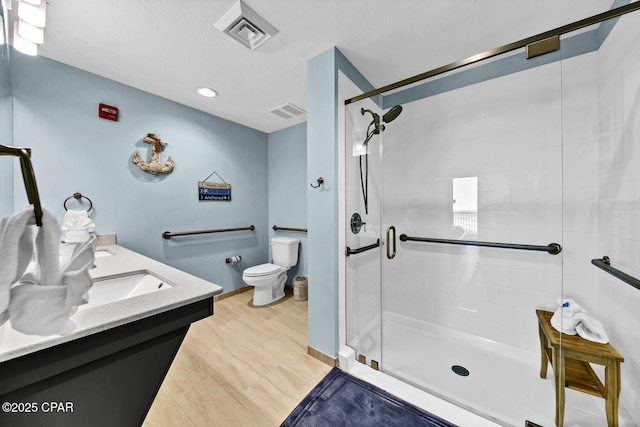 bathroom with visible vents, toilet, wood finished floors, and a shower stall