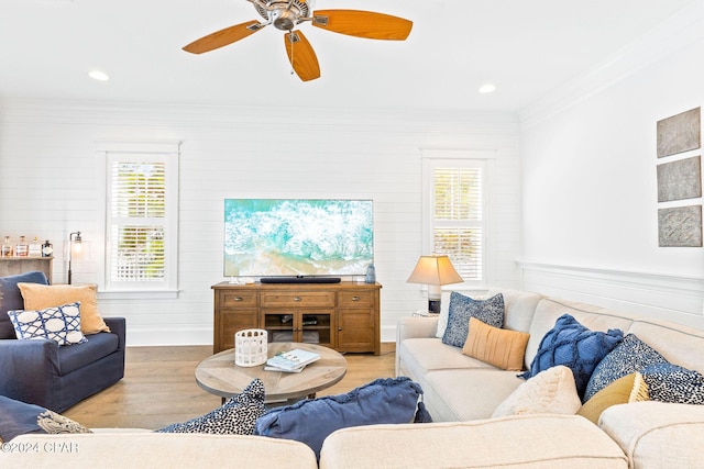 living area featuring light wood finished floors, baseboards, a ceiling fan, and ornamental molding