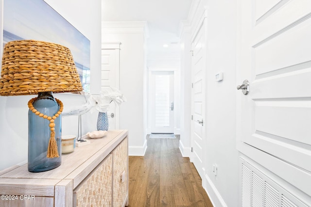 corridor with ornamental molding, baseboards, and wood finished floors