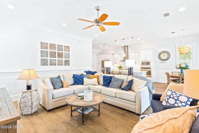 living room with crown molding, light wood-style floors, and visible vents