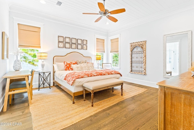 bedroom featuring visible vents, baseboards, wood finished floors, and crown molding