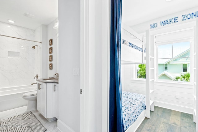 full bathroom featuring toilet, wood finished floors, baseboards, bathtub / shower combination, and vanity