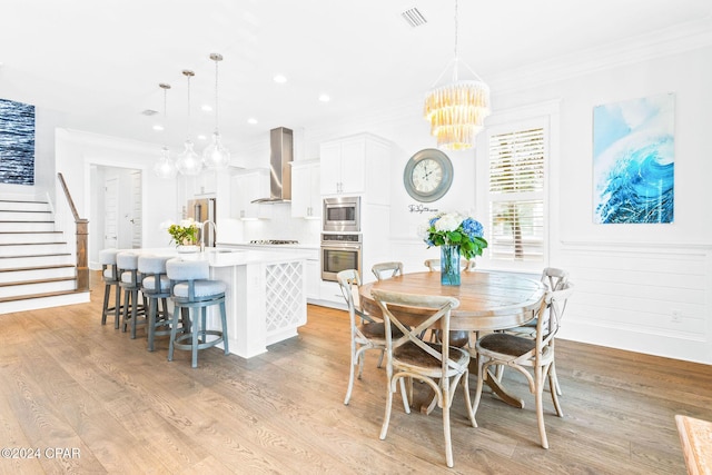 dining area featuring stairway, visible vents, light wood finished floors, crown molding, and a chandelier