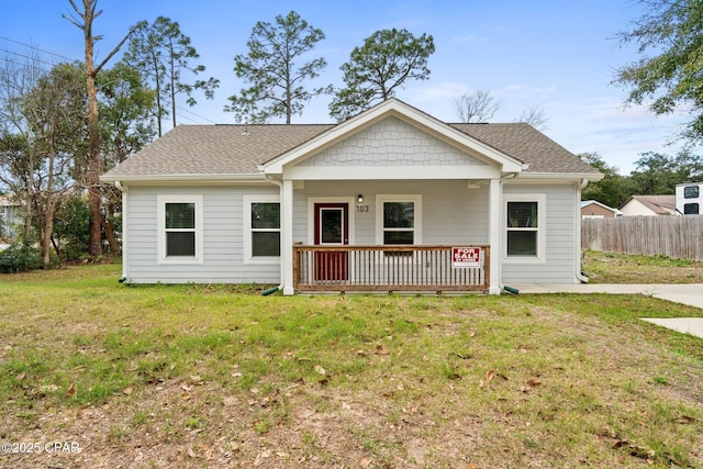 view of front facade featuring a porch, a shingled roof, a front yard, and fence