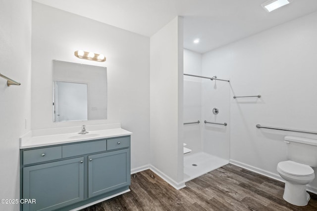 full bath featuring baseboards, walk in shower, toilet, wood finished floors, and vanity