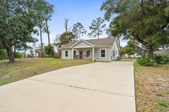 view of front facade featuring cooling unit, driveway, a porch, and a front yard