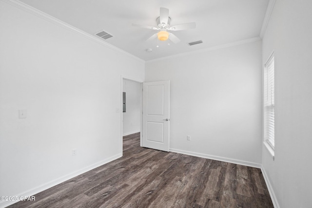 spare room with crown molding, wood finished floors, visible vents, and baseboards