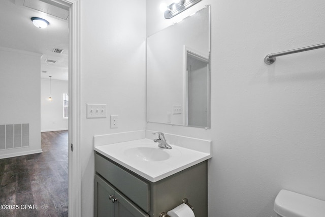 bathroom with visible vents, toilet, vanity, and wood finished floors