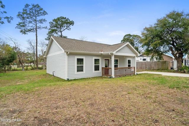 view of front of property featuring roof with shingles, a front lawn, and fence