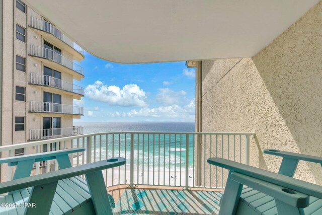 balcony featuring a view of the beach and a water view