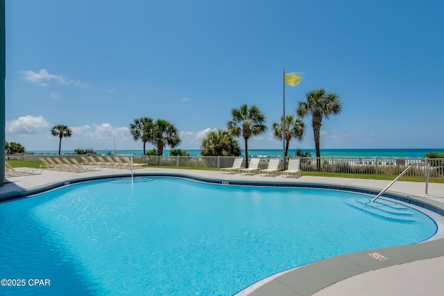 community pool with fence and a water view