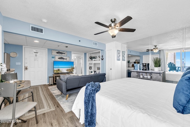 bedroom with visible vents, a paneled ceiling, a textured ceiling, and wood finished floors