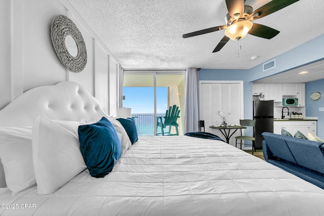 bedroom with visible vents, floor to ceiling windows, freestanding refrigerator, access to outside, and a sink