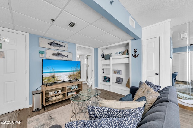 living room with visible vents, a paneled ceiling, and wood finished floors