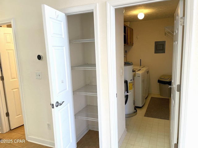 washroom with washer and clothes dryer, electric panel, a textured ceiling, water heater, and cabinet space