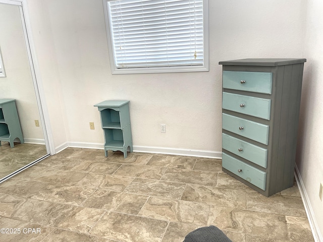 unfurnished bedroom with stone finish flooring and baseboards