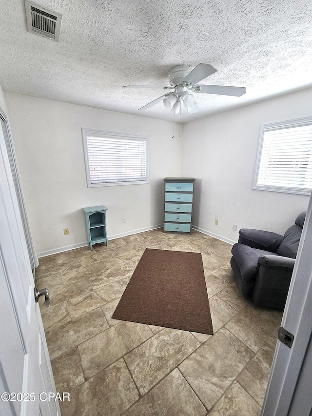 sitting room featuring baseboards, visible vents, and a textured ceiling