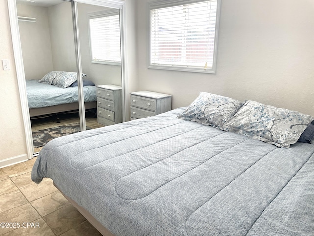 tiled bedroom featuring baseboards and a closet