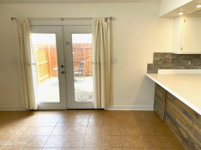 doorway featuring light tile patterned floors, french doors, and baseboards