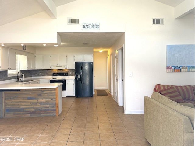 kitchen featuring visible vents, electric range oven, under cabinet range hood, and black fridge