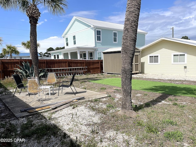 back of property featuring a patio area, a storage unit, fence, and an outbuilding