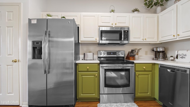 kitchen with green cabinetry, white cabinetry, appliances with stainless steel finishes, and light countertops