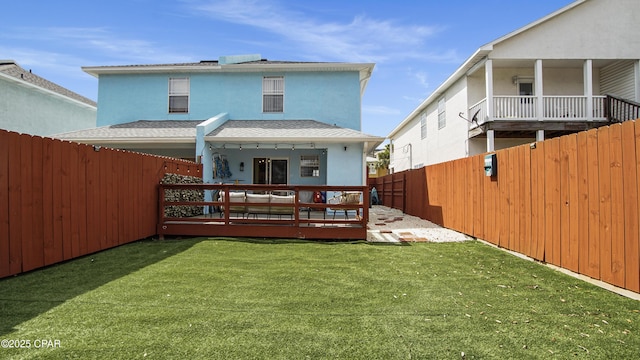 rear view of house with a fenced backyard, stucco siding, a yard, and roof with shingles