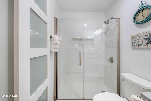bathroom featuring toilet and a shower stall