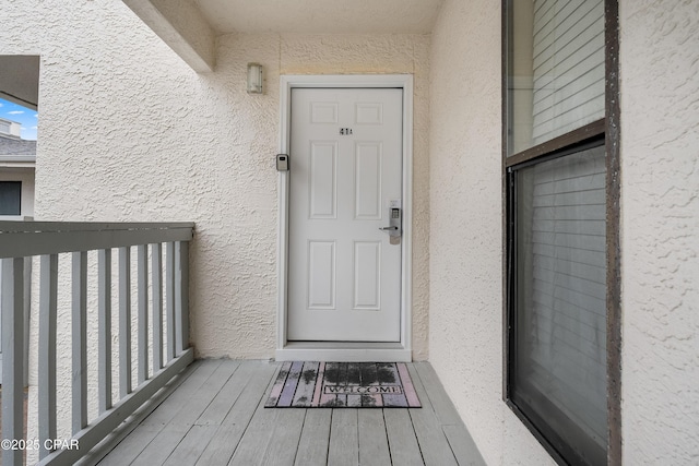 property entrance with stucco siding and a balcony