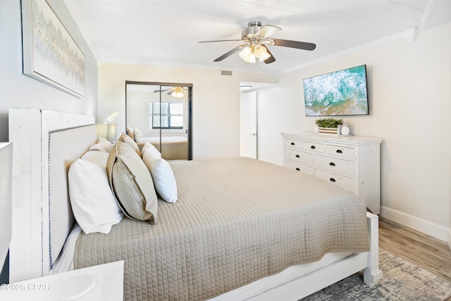 bedroom with visible vents, wood finished floors, a closet, crown molding, and baseboards