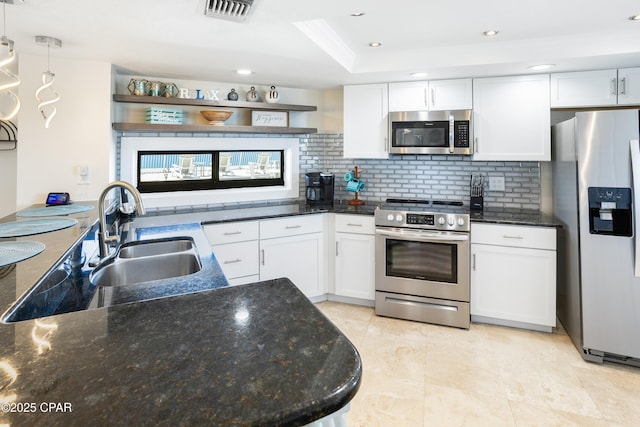 kitchen featuring visible vents, a sink, stainless steel appliances, white cabinetry, and tasteful backsplash