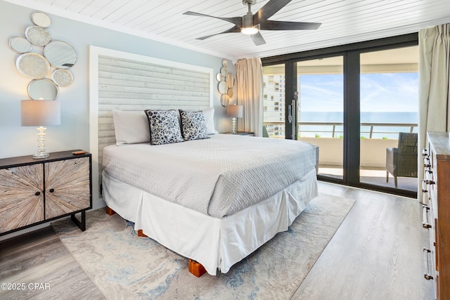 bedroom featuring expansive windows, light wood-style floors, wood ceiling, and access to outside