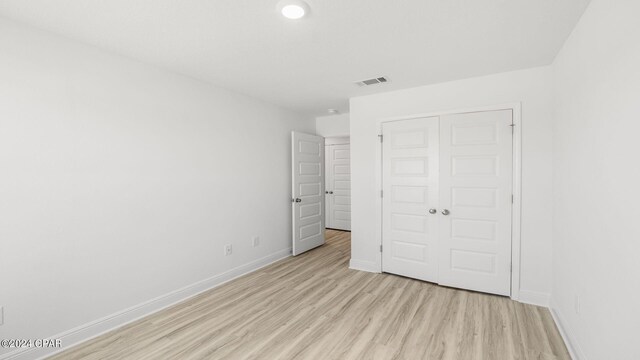 unfurnished bedroom featuring a closet, baseboards, light wood-type flooring, and visible vents