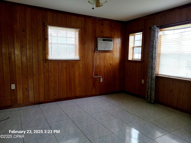 unfurnished room featuring a wall unit AC, wooden walls, baseboards, and a wealth of natural light