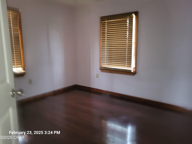 empty room with dark wood-type flooring and baseboards