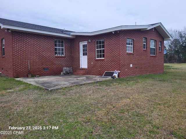 back of property with a yard, crawl space, brick siding, and a patio