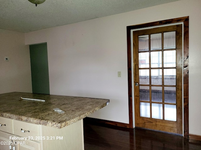 kitchen featuring baseboards, a textured ceiling, and wood finished floors