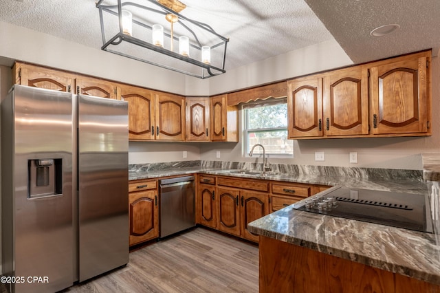 kitchen featuring brown cabinetry, appliances with stainless steel finishes, and a sink