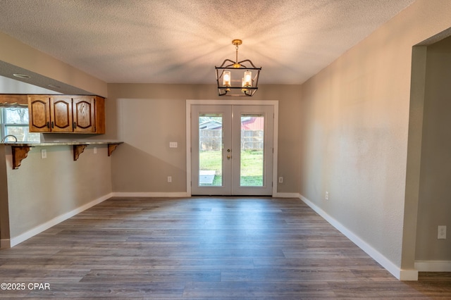 unfurnished dining area with baseboards, an inviting chandelier, and wood finished floors