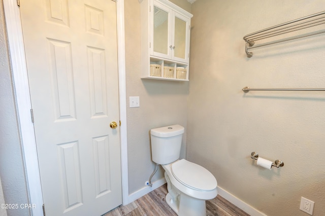 bathroom with baseboards, toilet, and wood finished floors