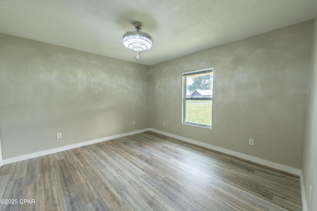 unfurnished room with baseboards and wood finished floors