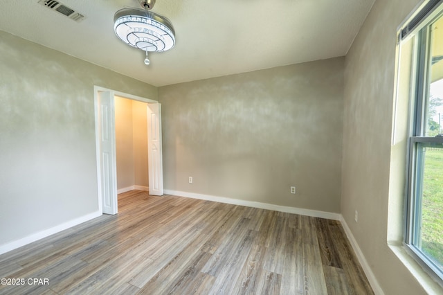 spare room featuring visible vents, baseboards, and wood finished floors