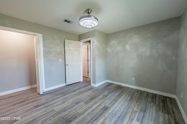 unfurnished bedroom with visible vents, baseboards, and wood finished floors