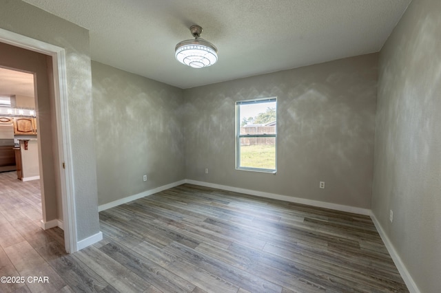 unfurnished room featuring wood finished floors, baseboards, and a textured ceiling