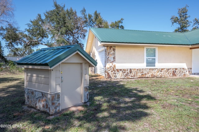 view of property exterior with metal roof, stone siding, and a lawn