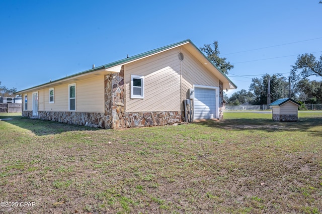 view of property exterior featuring a garage, a lawn, and fence