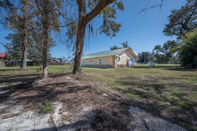 view of yard with an outbuilding, fence, a garage, and a shed